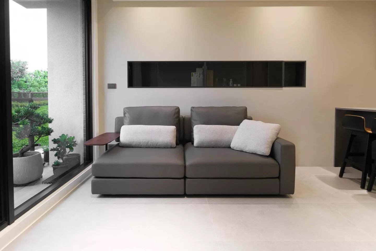 灰色三人沙發全牛皮材質搭配亞麻布料靠枕擺放於客廳